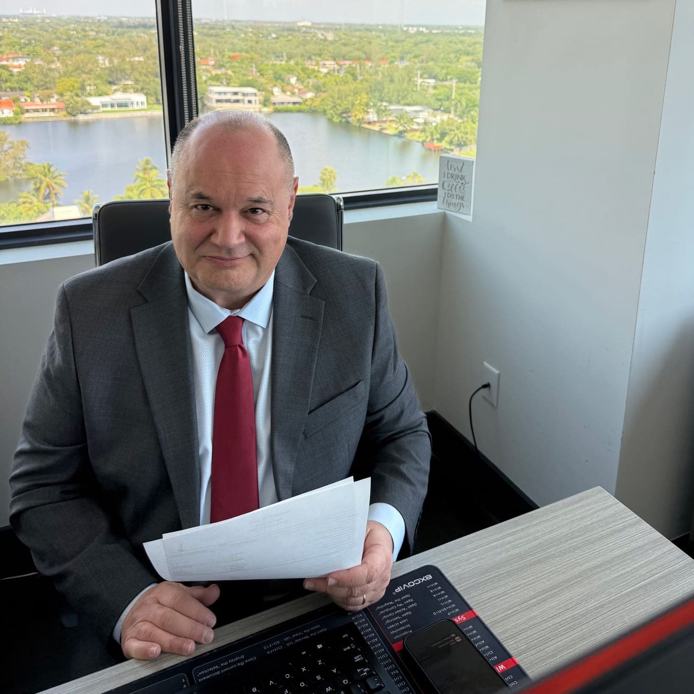 Jorge Schneider en su escritorio, revisando documentos, con vista a Miami